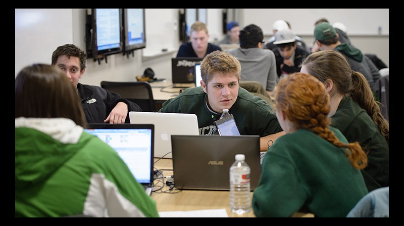 Groups of applied engineering students — many of them wearing Spartan gear — sit at study tables, deep in conversation.