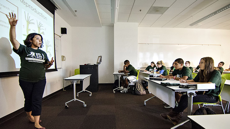 A professor instructs a classroom of biological sciences majors wearing Spartan-green shirts and listening attentively.