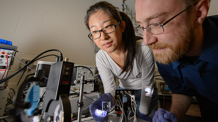 A professor and a student working toward a chemical engineering degree closely examine equipment.