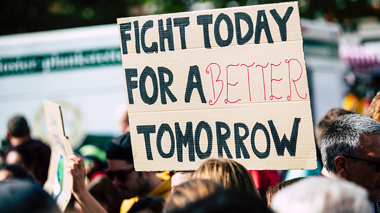 Learners interested in comparative politics gather in a protest — one sign reads, “Fight today for a better tomorrow.”