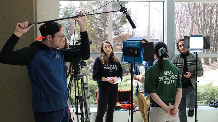 Digital storytelling students at Michigan State University filming a video with multiple cameras, lighting, and a boom mic.