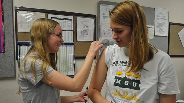 Two nutrition science majors practice doing physical assessments in an office.