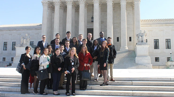 A large group of social policy majors smile in front of the United States Supreme Court Building.
