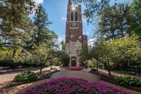 The Beaumont Tower at Michigan State University, which can be seen on the virtual tour, surrounded by trees and flowers on sunny spring day