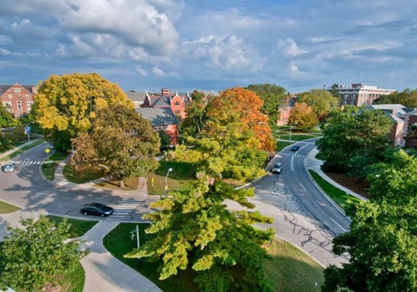 An aerial view of MIchigan State University's campus in the West Circle area with many green trees on the verge of changing color for the fall