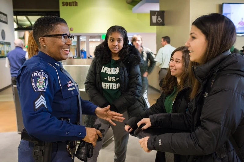An MSU police officer engaged in a friendly conversation with a group of students.