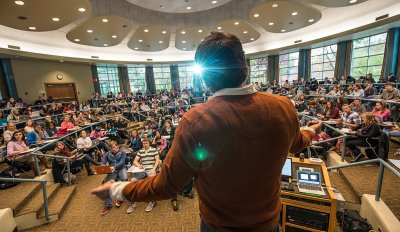 A professor faces a circular auditorium full of students while giving a lecture at Michigan State University